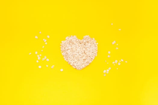 Creative flat lay concept top view of oatmeal flakes for healthy and vegetarian organic food for breakfast on a bright yellow color paper background with copy space in minimal style, template for text