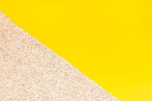 Creative flat lay concept top view of oatmeal flakes for healthy and vegetarian organic food for breakfast on a bright yellow color paper background with copy space in minimal style, template for text