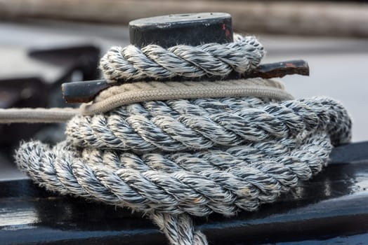 Mooring rope with a knotted end tied around a cleat on a wooden pier