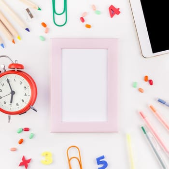 Square flat lay back to school concept blank tablet with alarm clock, color school and office supplies on white table background with copy space, frame, template for text or design