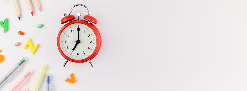 Long wide banner back to school concept with alarm clock, color school and office supplies on white table background with copy space, frame, template for text or design
