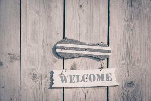 Wooden welcome sign in rustic style hanging on plank door