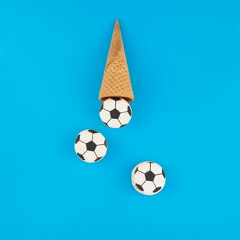 Square Creative flat lay top view of ice cream waffle cones with soccer balls macarons on bright bold blue background with copy space in minimal style, concept of football games for children birthday