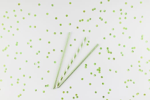 Holiday pattern flat lay top view Xmas Christmas New Year celebration drinking cocktail fun party straws green golden sparkles glitter white background. Template for greeting card your text design