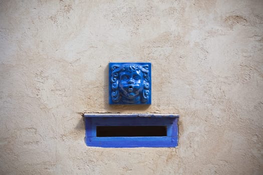 Plaster wall with blue decorative letter slot mailbox. Horizontal shot