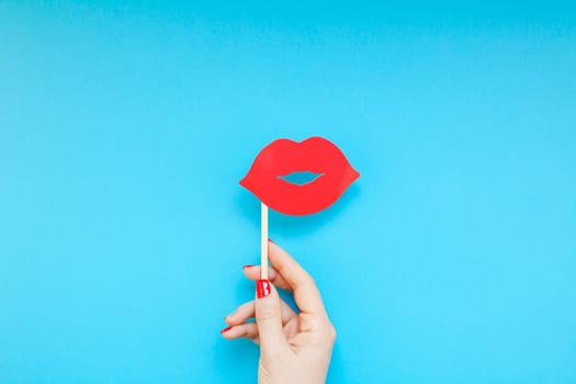 Creative overhead top view retro stylish red paper photo booth props female lips in hand turquoise background copy space. Birthday parties and weddings valentine day template