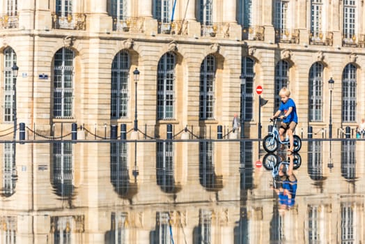 FRANCE, BORDEAUX - SEPTEMBER 20: Children having fun in a mirror fountain in front of Place de la Bourse in Bordeaux, France on September 20, 2015