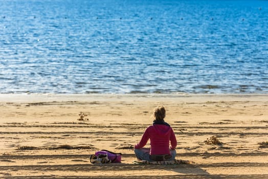FRANCE, ARCACHON - SEPTEMBER 18: girl is sitting on the sand beach and looking at the blue water on September 18, 2015