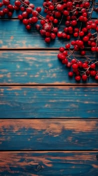 Vibrant red winter berries on rustic blue wooden planks with weathered texture, perfect for seasonal decor or holiday designs with copy space.