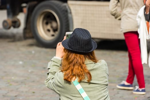BELGIUM, BRUSSELS - MAY 25: Back side of a young woman taking a photo with her camera on May 25, 2015
