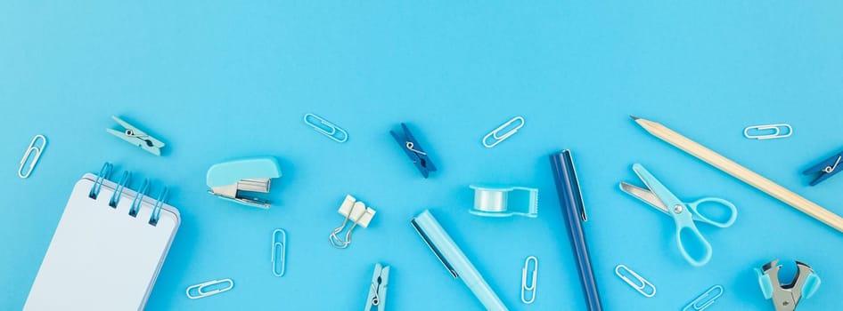 Top view flat lay of workspace desk styled design school and office supplies with copy space turquoise blue color paper background minimal style. Long wide banner Template feminine blog social media