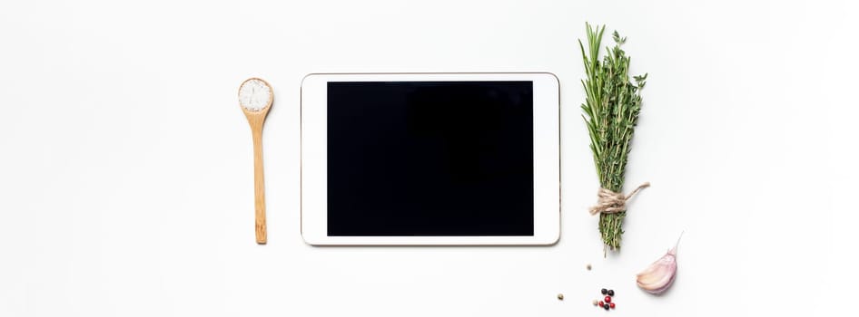 Flat lay overhead view tablet PC gadget mockup blank text space on white background with greens herbs and spices. Menu design food blog recipe cookbook or delivery app with cooking ingredients