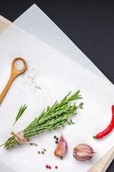 Flat lay overhead top view of greens herbs and spices on wooden cutting board on black background with copy space. Menu frame design food background with cooking ingredients