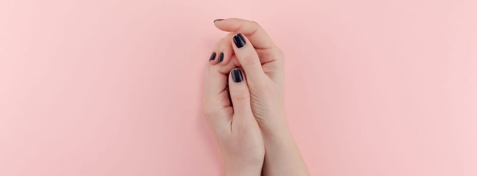 Stylish trendy female black manicure. Beautiful young woman's hands on millennial pink pastel background. Beauty and SPA concept. Banner Template for feminine blog social media