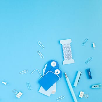 Top view flat lay of workspace desk styled design handcrafting holiday decor tags office supplies with copy space turquoise blue color paper background. Square Template for feminine blog social media