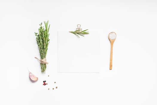Flat lay overhead view blank recipe paper page with clip mockup text space invitation card on white background with greens herbs and spices. Menu recipe book food blog design with cooking ingredients