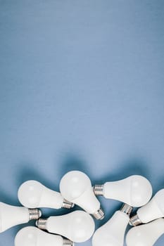 Energy-saving and eco-friendly life in conceptual frame pattern. Creative top view flat lay of LED light bulbs composition with copy space on blue background in minimal style.