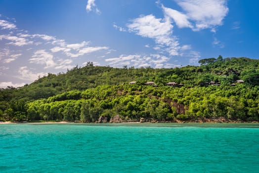 View of Seychelles coastline with houses in the forest. Horizontal shot