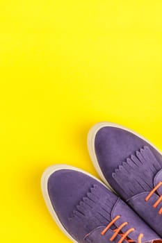 Flat lay of suede shoes on bold yellow paper background with copy space. Overhead view of woman casual outfit. Trendy hipster look top view