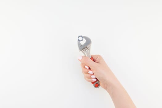 Creative image of woman hand with pastel manicure polish holding spanner with copy space isolated on white background in minimalism style. Repair or improvement feminism concept
