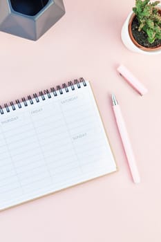 Top view flat lay of workspace desk styled design office supplies and cactuses succulents with copy space millennial pink color paper background minimal style. Template for feminine blog social media