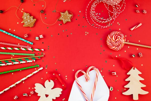 New Year or Christmas decoration flat lay top view Xmas holiday celebration handmade decor wooden toys sweets golden stars glitter on red paper background. Template frame for greeting card your design
