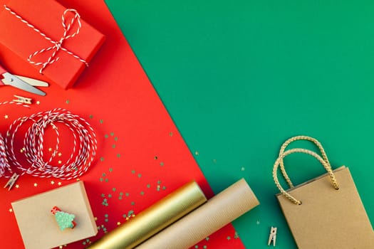 New Year or Christmas presents preparation DIY flat lay top view Xmas holiday celebration handmade gift boxes on red green paper background. Template mockup for greeting card or your text design 2019