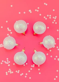 New Year or Christmas pattern flat lay top view Xmas holiday celebration pearl decorative toy balls sparkles confetti pink paper background copy space Template frame for greeting card your text design