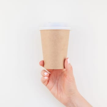 Square mock up image of woman hand holding craft paper coffee cup with copy space isolated on white background in minimalism style. Template for feminine blog, social media