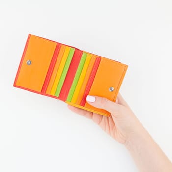 Woman hand with pastel manicure polish holding bright red leather wallet isolated on white background with copy space minimalism style. Square Template for feminine beauty blog social financial media