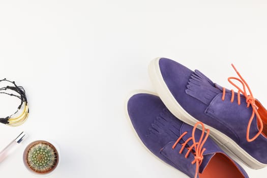 Flat lay of trendy suede shoes, female accessories and cactus on white background with copy space. Overhead view of woman casual outfit. Trendy hipster look top view