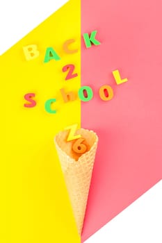 Creative flat lay back to school concept with waffle cone and welcome letters message on bright yellow and pink paper background with copy space, template for text or design