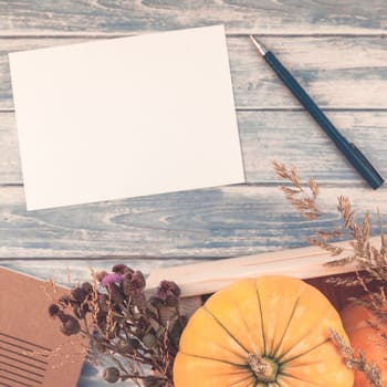 Square Top view of autumn orange pumpkins and dry flowers with grass thanksgiving background over blue toned wooden table with blank letter mock up and copy space in rustic style, template for text