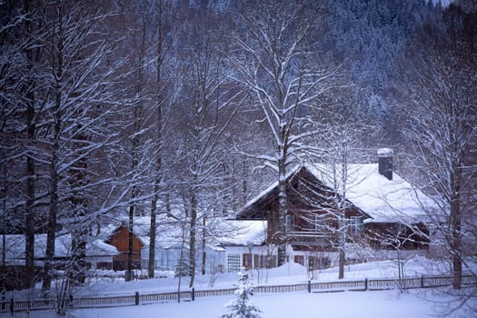 Fairy tale landscape: snowy Alpine house in the woods.ÊToned and vignetted image as postcard