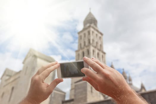 Tourist hands holding smart phone taking photo of Perigueux, France
