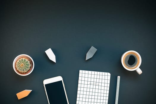 Top view flat lay feminine desk workspace with coffee, smartphone and office supplies with copy space on black background. Creative template for blog social media