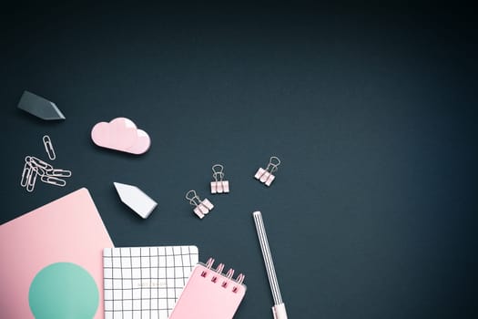 Top view flat lay feminine desk workspace styled pink colored objects design office supplies with copy space on black background. Template for blog social media