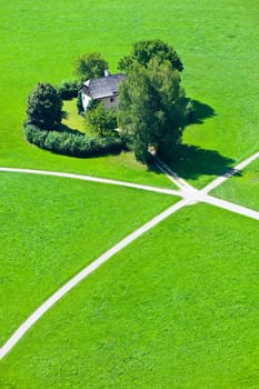 Intersection of five walking paths and a house in green field