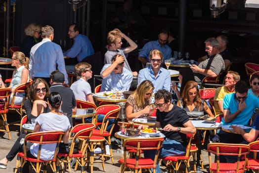 FRANCE, PARIS - JUNE 06: Parisians and tourists enjoy food and drinks in cafe sidewalk in Paris France on June 06, 2015.