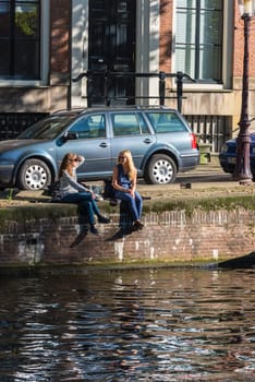 NETHERLANDS, AMSTERDAM - OCTOBER 2: Girls are sitting on the canal bank in Amsterdam on October 2, 2015