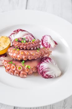 Portion of grilled Octopus with lemon and lettuce