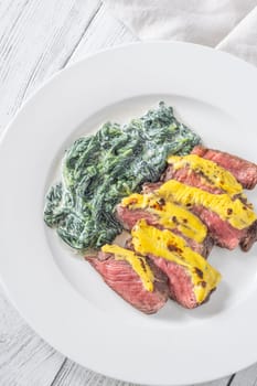 Cheese topped beef steak with creamy spinach