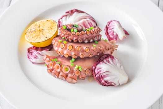 Portion of grilled Octopus with lemon and lettuce