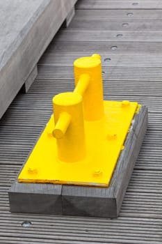 Closeup of Bright Yellow Boat Cleat on a dock pier. Vertical shot