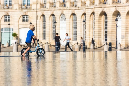 FRANCE, BORDEAUX - SEPTEMBER 20: Children having fun in a mirror fountain in front of Place de la Bourse in Bordeaux, France on September 20, 2015