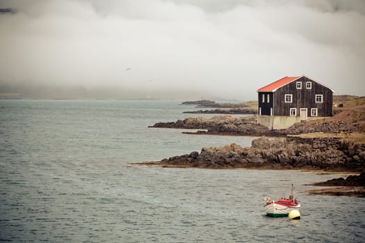 Lonely Black Wooden House and boat at coastlineÊin East Iceland. Horizontal toned shot