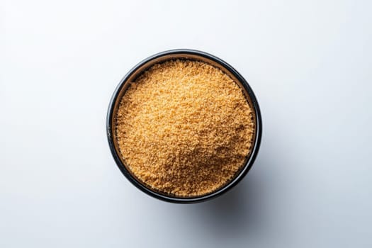 A black bowl filled with finely crushed graham cracker crumbs is prominently displayed on a light surface, showcasing the golden-brown texture and fine consistency of the crumbs.
