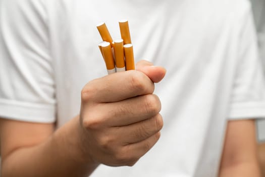 Asian man holding cigarette in hand, no smoking.