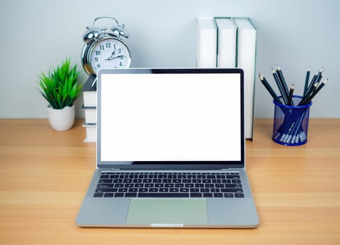 Space for copying your text. Laptop with blank screen on white table and office supplies on wooden background. Workspace and copy space. Desk with office supplies.