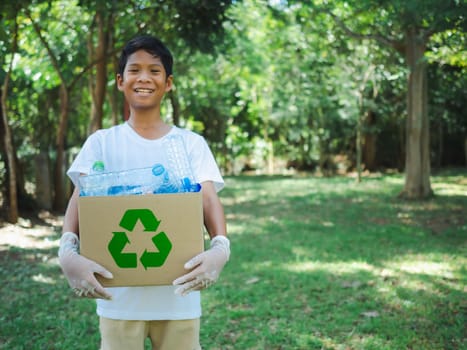 Boy hold cardboard boxes for recycling and holding a recycle bin with plastic bottles in the outdoors, Reduction environmental pollution and recycle concept, Plastic-free, Junk food plastic packaging.